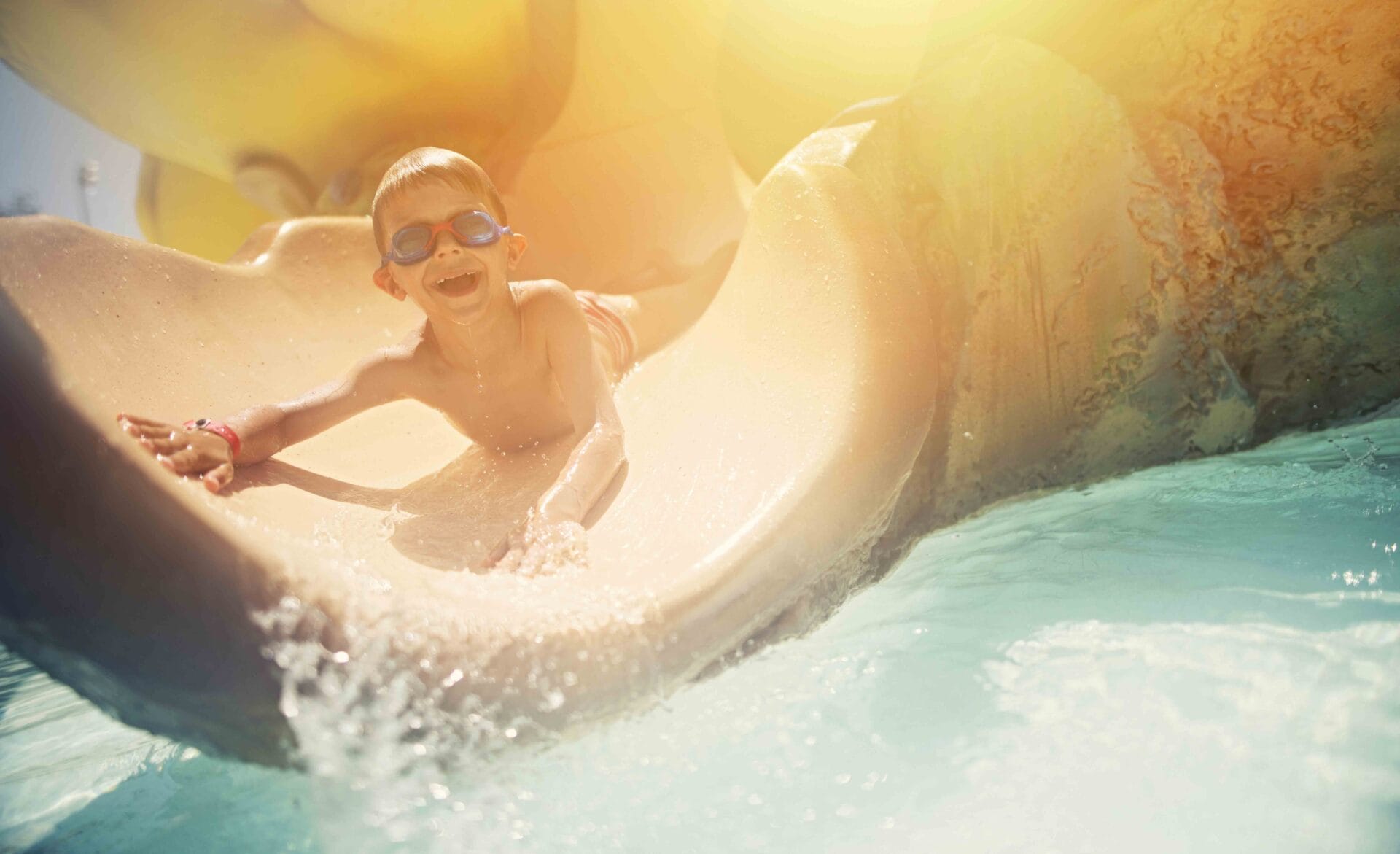 Little boy sliding on water slide.