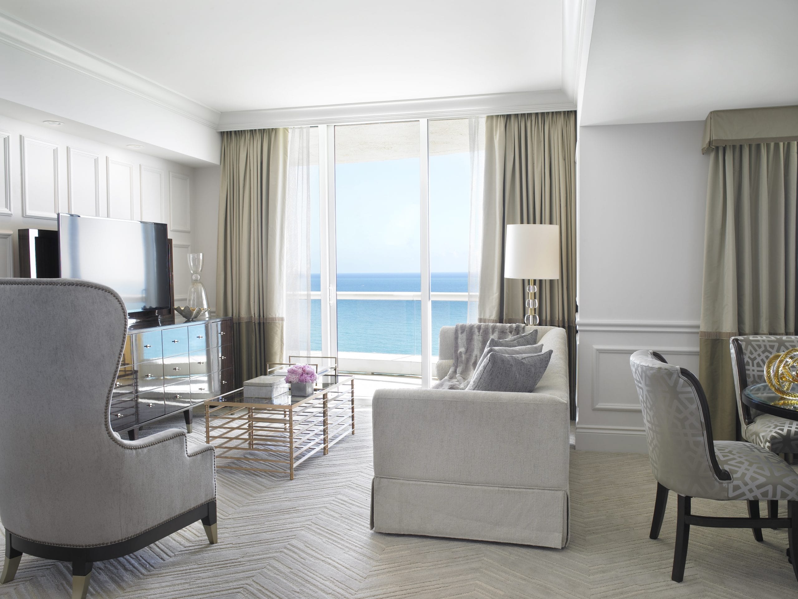 Luxury ocean-view suite featuring a stylish living area, elegant furnishings, floor-to-ceiling windows, and panoramic views of the Atlantic Ocean at Acqualina Resort Miami Beach.