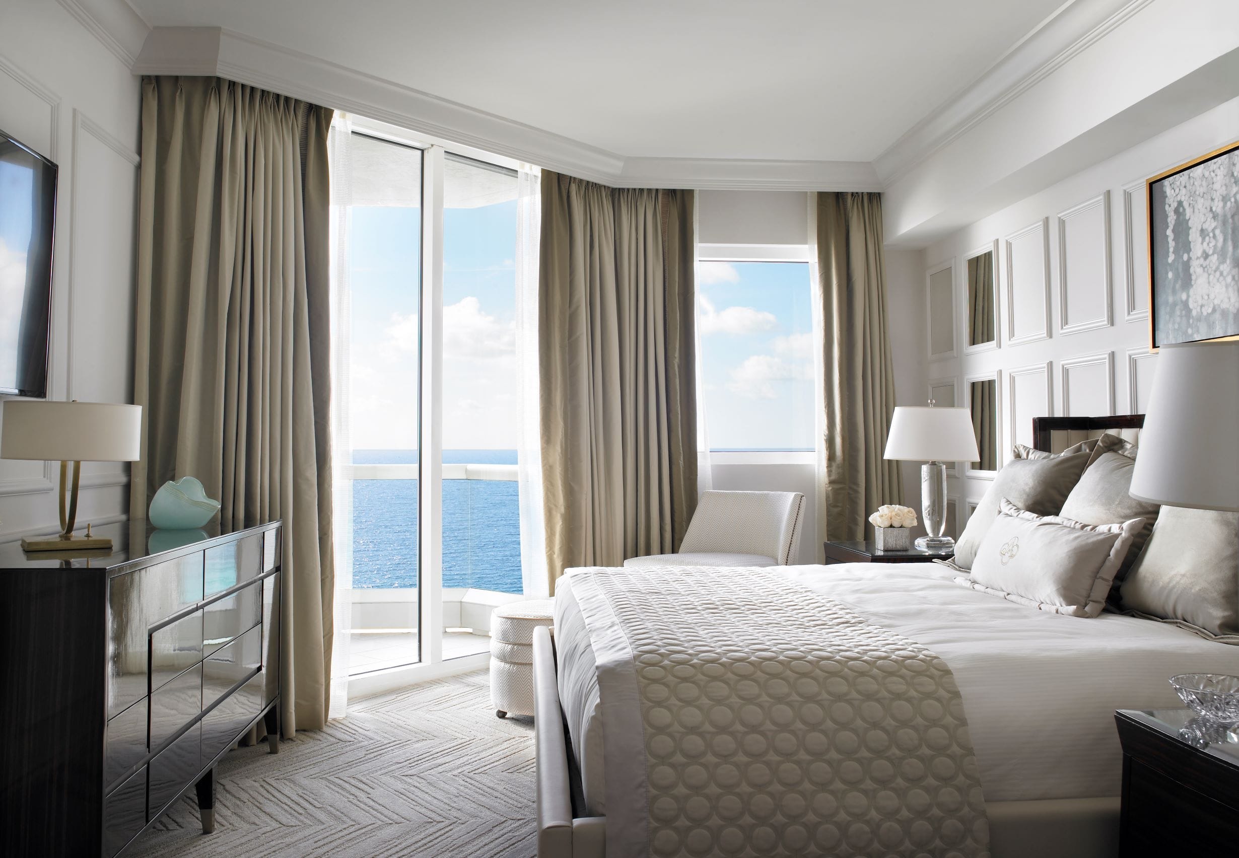 Luxury oceanfront bedroom featuring two plush double beds, elegant furnishings, floor-to-ceiling windows, and panoramic Atlantic Ocean views at Acqualina Resort Miami Beach.