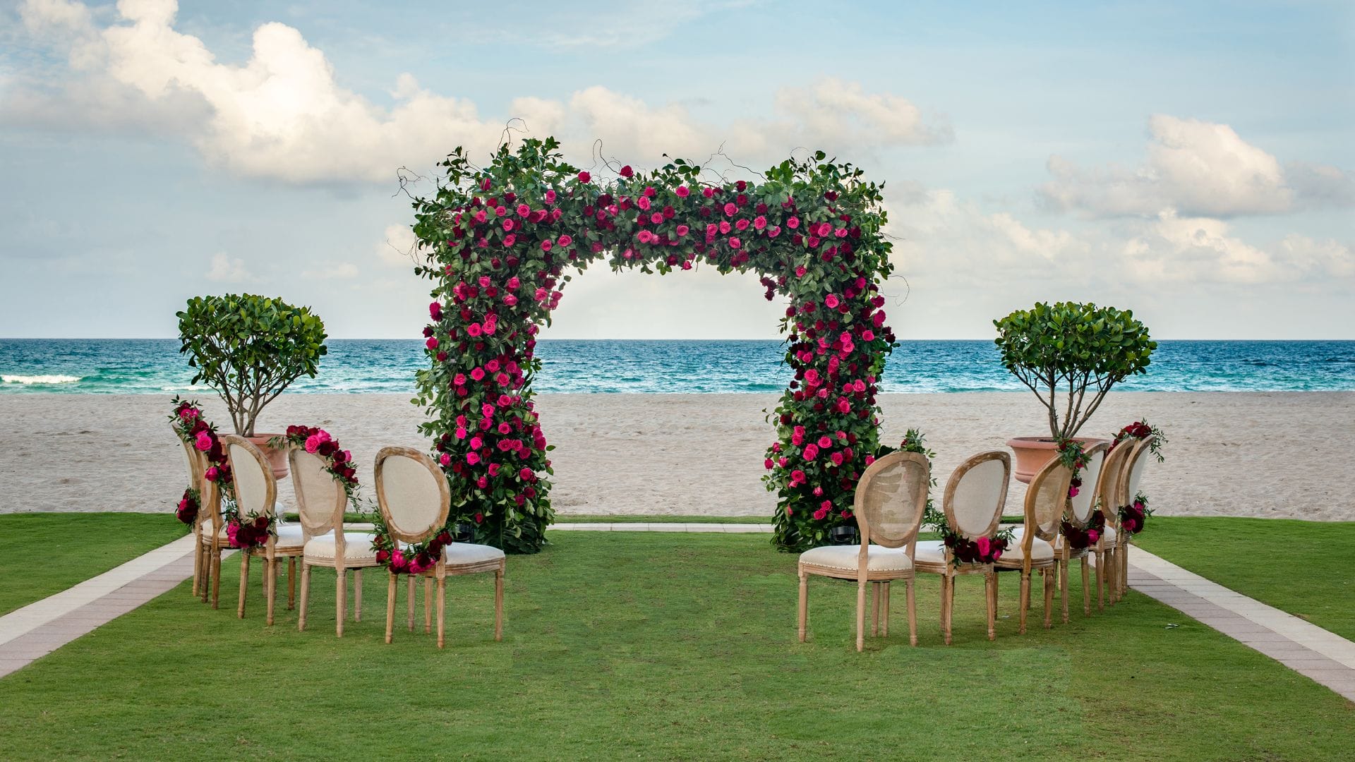 Beachfront wedding ceremony setup with floral arch at Acqualina Resort